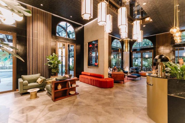 Lujoso lobby del Hotel Marquee Medellín con sofás rojos, lámparas colgantes y decoración moderna