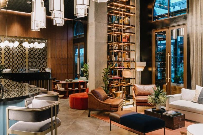 Elegante lobby lounge del Hotel Marquee Medellín con sofás de cuero, estanterías doradas y lámparas de cristal