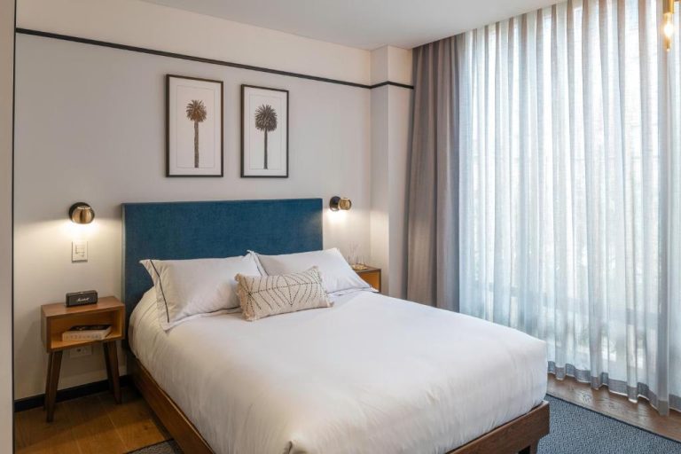 Habitación con cama king size y cabecero azul en HAB Hotel Bogotá con iluminación cálida