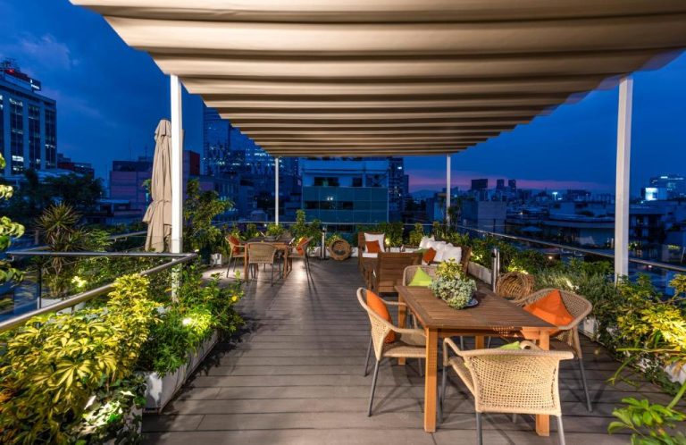Terraza rooftop del Reforma Guest House con mesas, vegetación y vistas panorámicas de la ciudad al atardecer