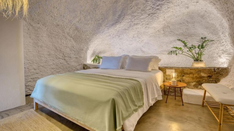 Habitación cueva con cama doble y paredes de piedra blanca en Socalco Nature Calheta