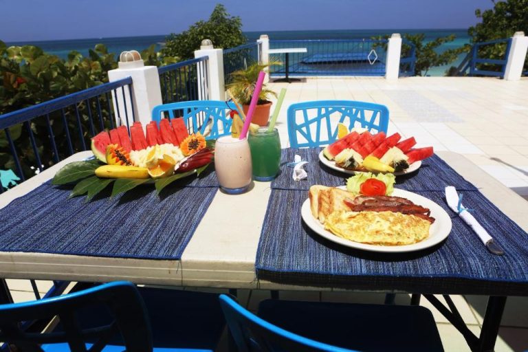 Desayuno tropical con frutas frescas y tortilla en terraza frente al mar del Negril Treehouse Resort