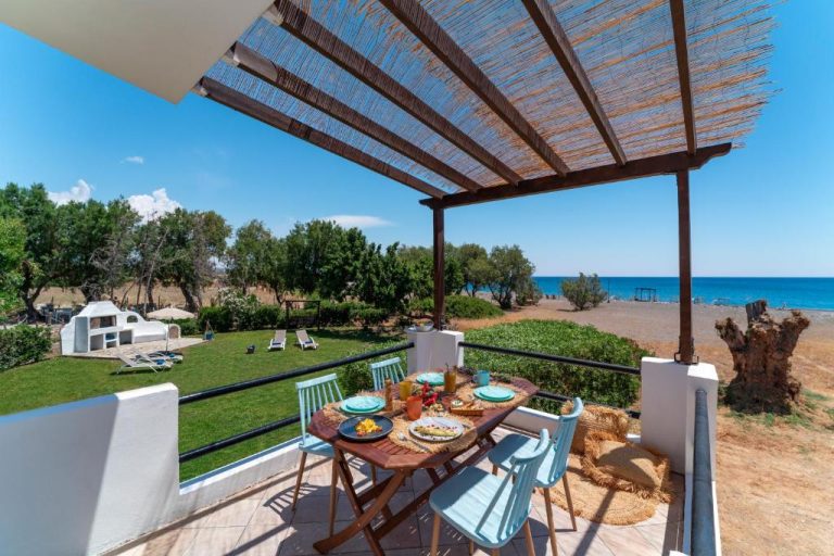 Terraza con mesa y sillas azules con vistas al jardín y mar en Eco Beach And Magic Garden Hotel