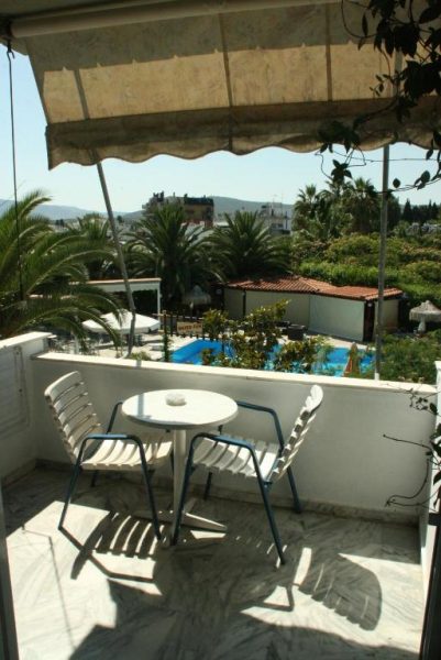 Terraza con mesa y sillas del Batis Hotel con vistas a la piscina exterior y palmeras
