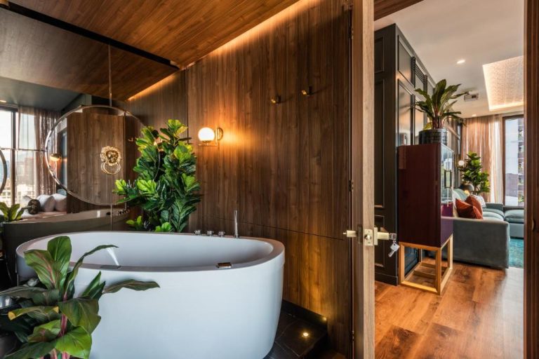 Bañera independiente de lujo con plantas tropicales y paredes de madera en Hotel Marquee Medellín
