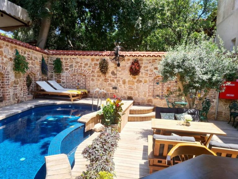 Piscina exterior con terraza de madera y muro de piedra histórico en Hotel Lykia Old Town Antalya