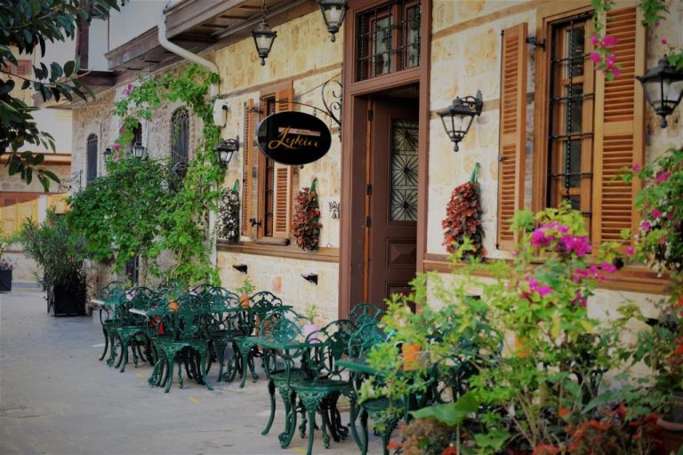 Terraza exterior con sillas de hierro forjado y jardín florido del Hotel Lykia Old Town Antalya