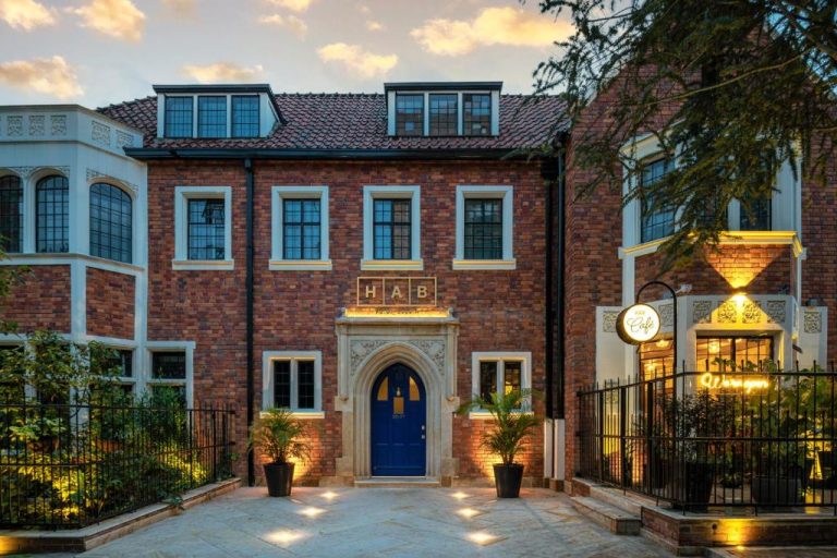 Fachada exterior de ladrillo del HAB Hotel Bogotá con entrada arqueada y puerta azul al atardecer