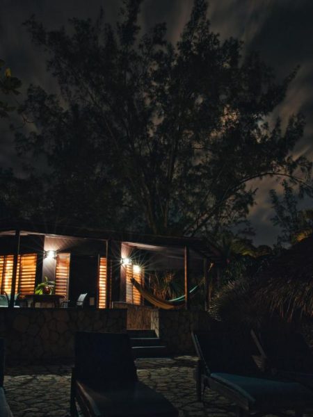 Bungalow de madera iluminado por la noche con hamaca en el Catcha Falling Star, Jamaica