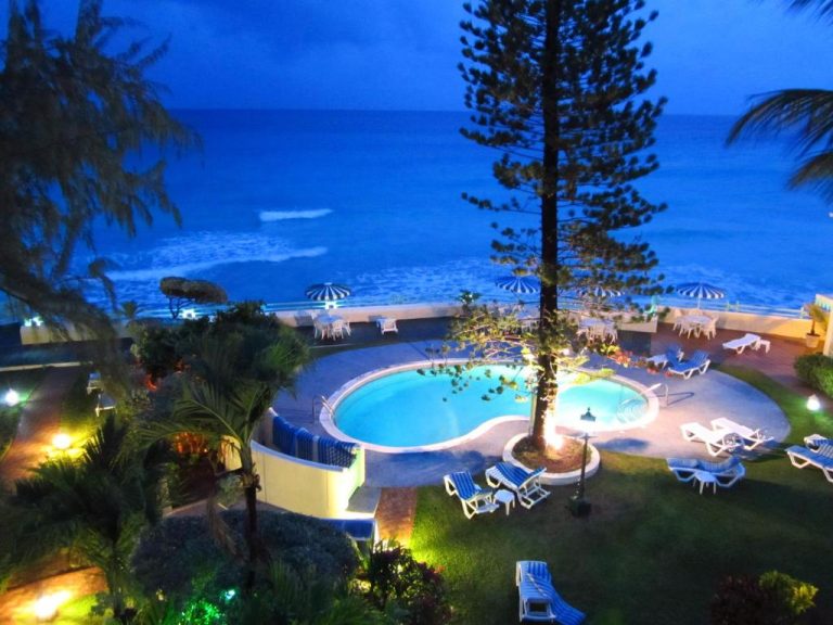 Piscina exterior iluminada de noche con vistas al mar en Blue Orchids Beach Hotel Barbados