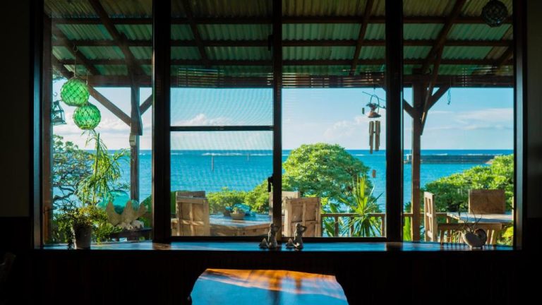 Vista panorámica al mar desde el interior del Sunset Beach House con terraza y vegetación tropical