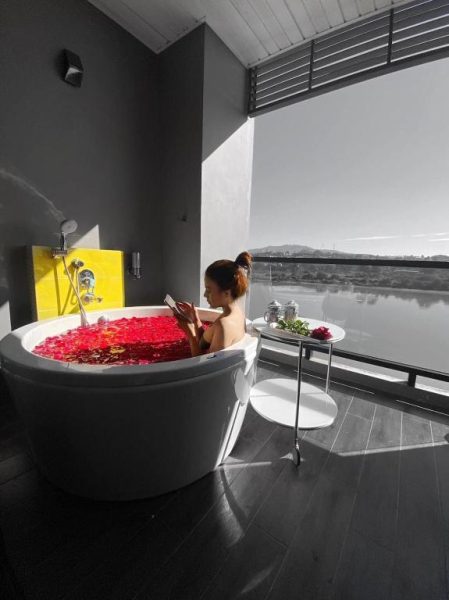 Baño onsen con pétalos de rosas y vista al río en Chiangkhong Teak Garden Riverfront Onsen Hotel