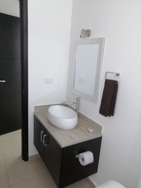 Baño moderno con lavabo sobre encimera y espejo decorativo en Condo Kiaraluna