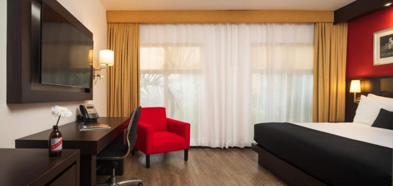 Habitación deluxe del S Hotel Kingston con cama doble, silla roja y escritorio de trabajo