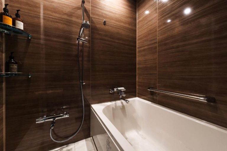 Baño moderno con bañera blanca y ducha teléfono en Prostyle Ryokan Naha Kenchou Mae