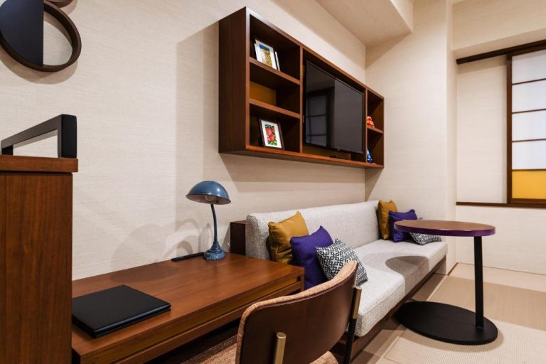 Salón con sofá, escritorio de madera y televisión empotrada en Prostyle Ryokan Naha Kenchou Mae