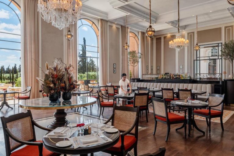 Elegante restaurante interior del The Oberoi Marrakech con lámparas de cristal y sillas rojas