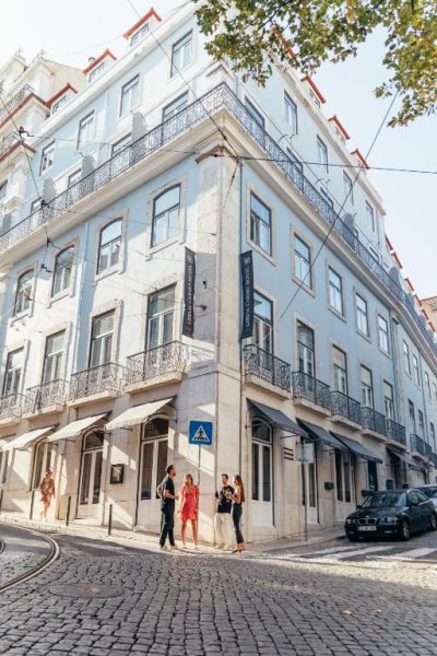 Fachada exterior del Lisboa Carmo Hotel con turistas en las calles adoquinadas del centro histórico de Lisboa