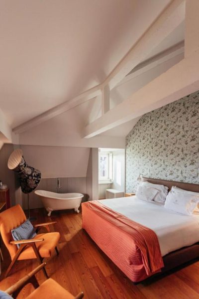 Habitación ático con bañera exenta, cama doble y papel pintado floral en Lisboa Carmo Hotel