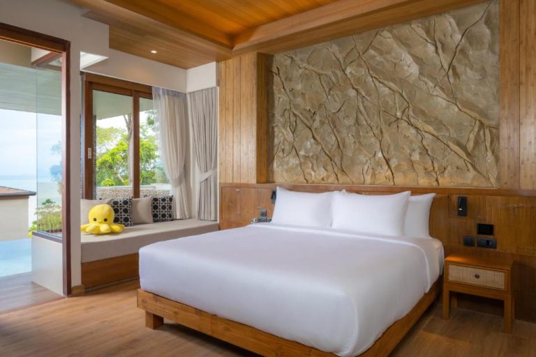 Habitación de lujo con pared de piedra natural y cama king size en SINAE Phuket Luxury Hotel