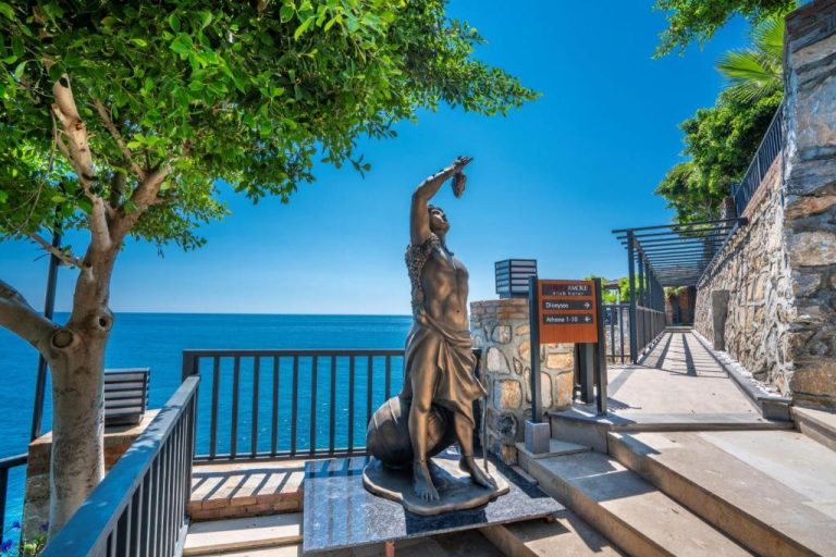 Estatua de bronce frente al mar en el Porto Amore Club Hotel con camino hacia las villas Dionysus y Athena