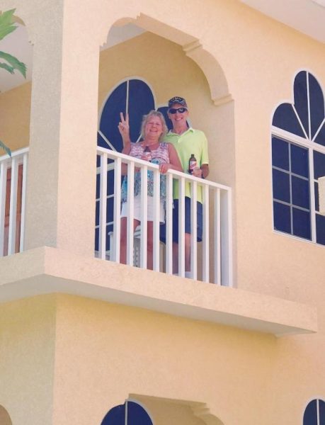 Pareja posando con señal de paz en el balcón exterior de Sommerville Resorts con vistas al complejo