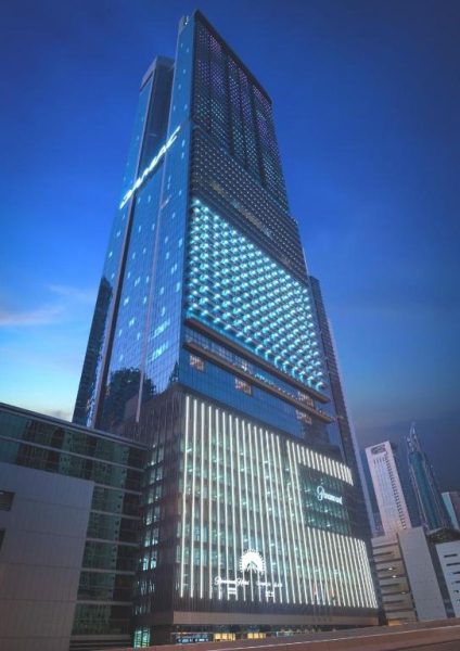 Fachada iluminada de noche del Paramount Hotel Midtown en Dubai con espectacular arquitectura moderna