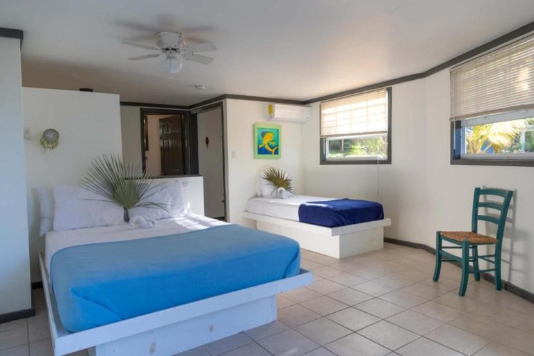 Habitación doble con camas azules y decoración tropical en The Sunset Cove and Rainbow Room