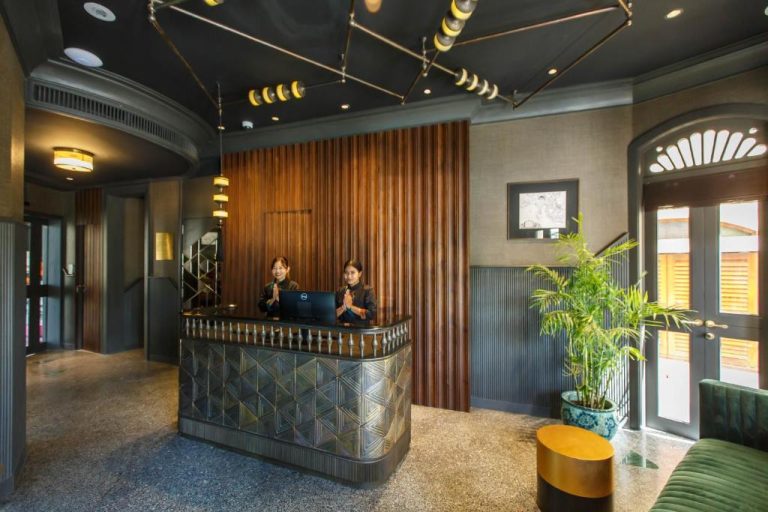 Recepción elegante del Hotel Verdigris con dos recepcionistas en actitud de bienvenida y decoración asiática