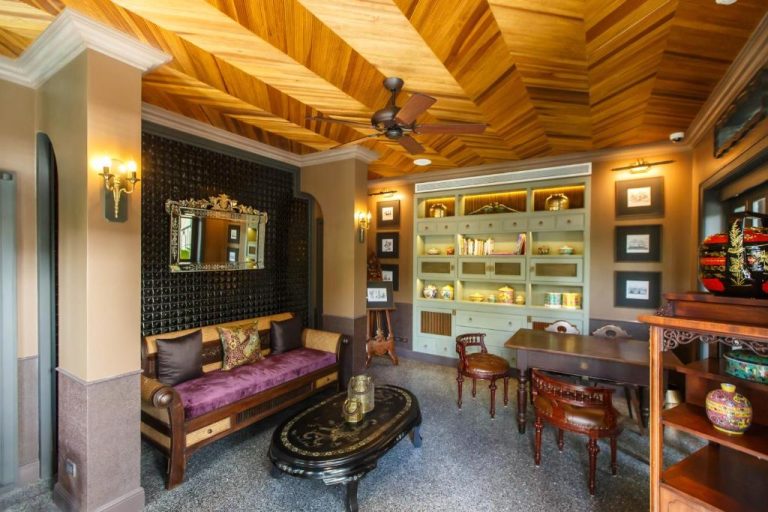 Salón colonial con techo de madera, sofá y librería iluminada del Hotel Verdigris