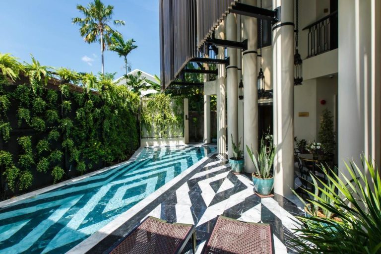 Piscina exterior con mosaico geométrico en blanco y negro del Hotel Verdigris rodeada de vegetación tropical