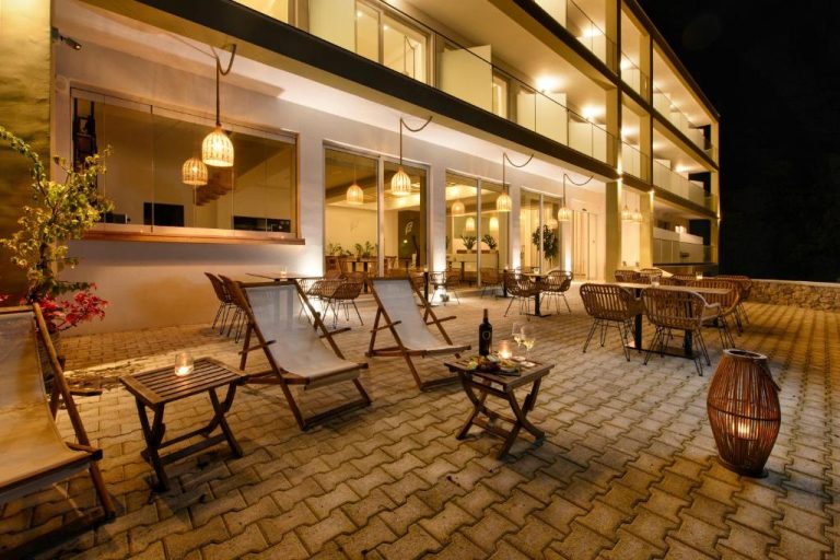 Terraza exterior nocturna con tumbonas y mesas del Eleals Boutique Hotel iluminada con velas y lámparas