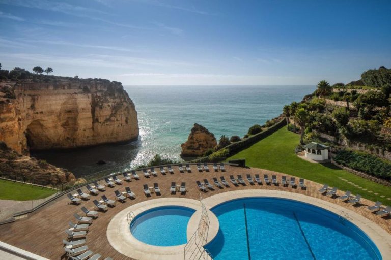 Piscina exterior con tumbonas y vistas al acantilado y mar del Tivoli Carvoeiro en el Algarve