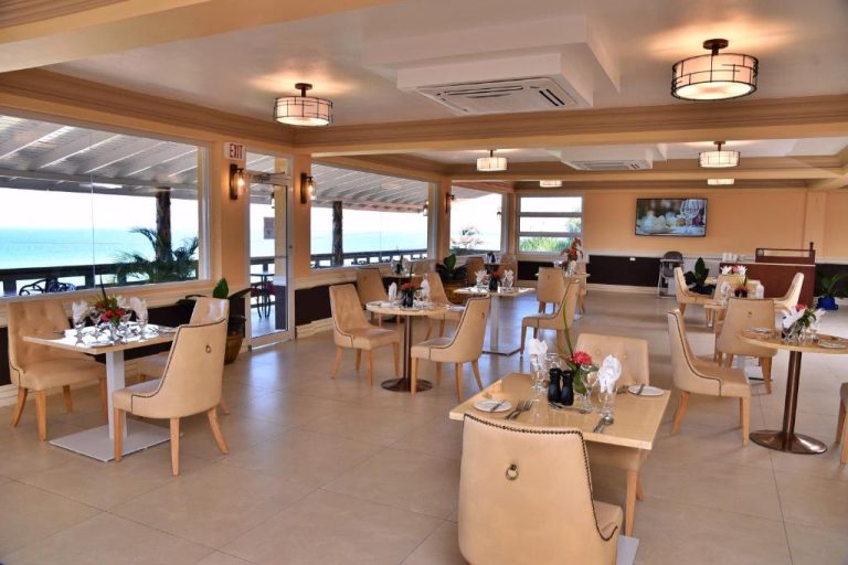 Restaurante elegante con vistas al mar del Hotel Grand A View, mesas decoradas y sillas beige