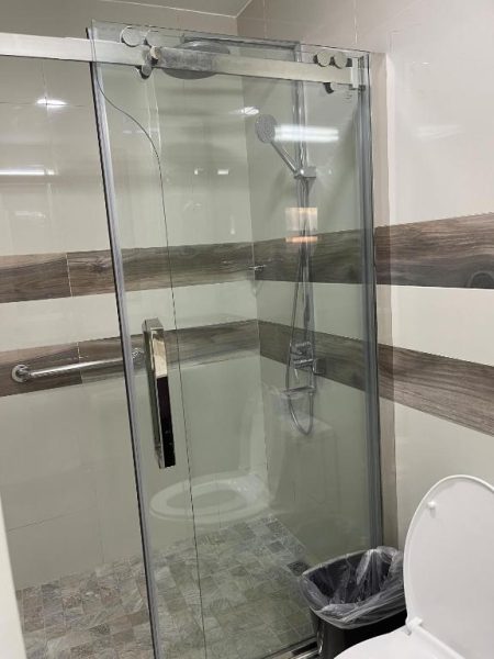 Cabina de ducha con mampara de cristal y sanitario en el baño del Hotel Grand A View