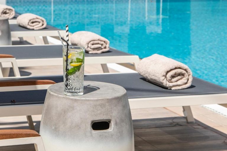 Zona de piscina con tumbonas, toallas y cóctel de mojito en el KoSea Boutique Hotel