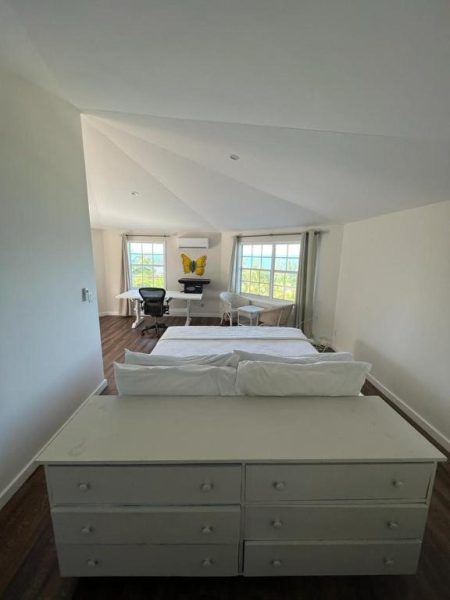 Habitación amplia con cama doble, cómoda blanca y escritorio en The Sunset Cove and Rainbow Room