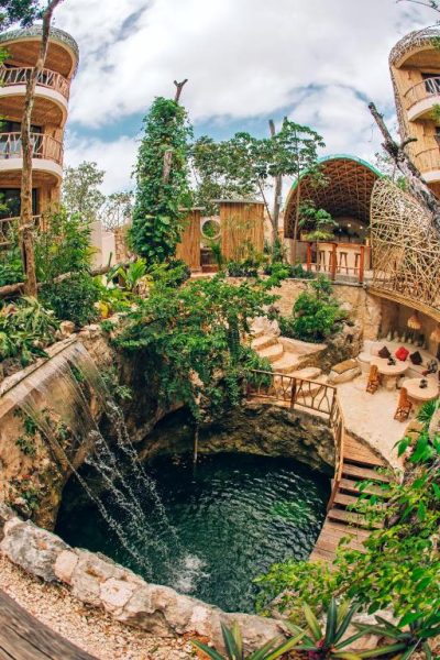 Cenote natural con cascada y arquitectura de bambú en el Kan Tulum Hotel rodeado de vegetación tropical