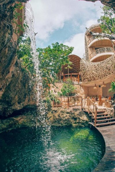 Cenote natural con cascada y arquitectura de bambú en Kan Tulum Hotel, Tulum México