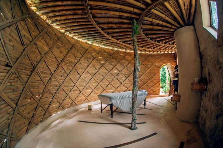 Sala de masajes con estructura de bambú y camilla en el Kan Tulum Hotel, rodeada de naturaleza