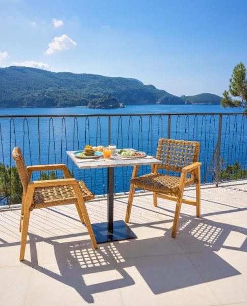 Terraza con mesa y sillas de ratán con vistas al mar azul en Akrotiri Beach Resort & Spa