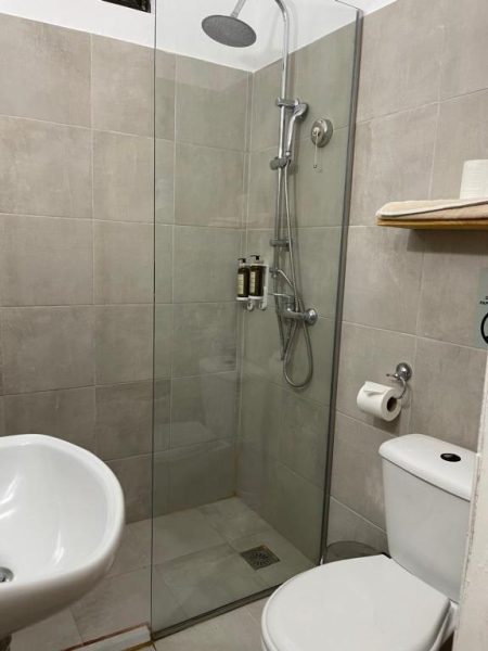 Baño moderno con ducha de lluvia, lavabo y aseo en Eco Beach And Magic Garden Hotel