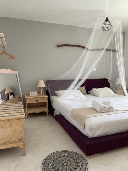 Habitación doble con cama con dosel y decoración rústica en Eco Beach And Magic Garden Hotel