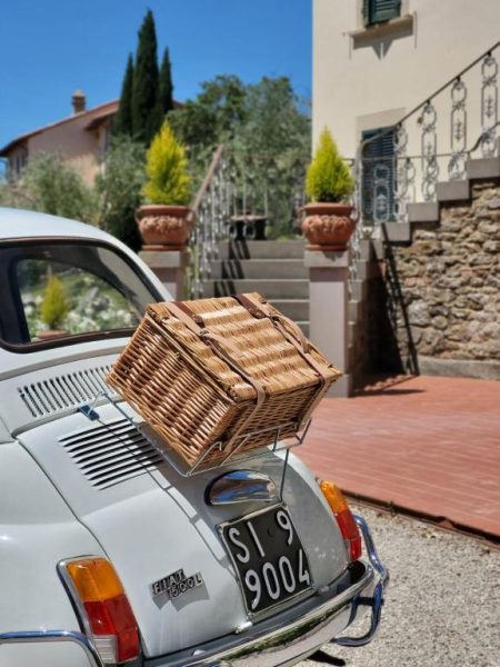 Fiat 500 clásico con cesta de picnic en la entrada del Cortona Resort & Spa en la Toscana