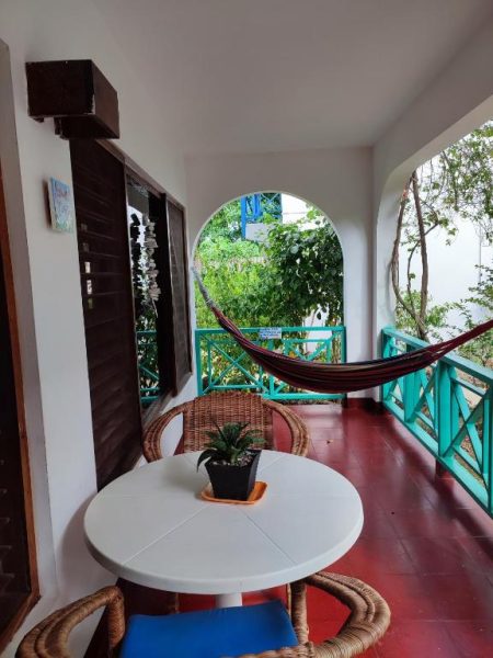 Terraza con hamaca, mesa y sillas de mimbre con vista al jardín tropical en Ltu Garden