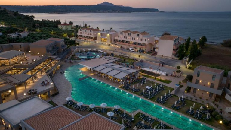 Vista aérea de la piscina exterior iluminada del Kiani Beach Resort Family All Inclusive al atardecer
