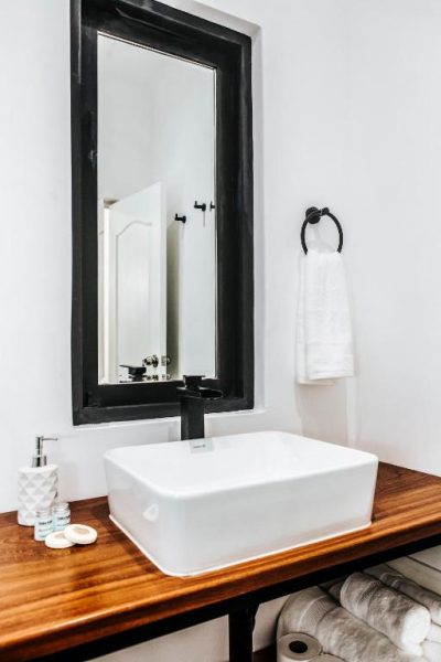 Baño elegante con lavabo sobre encimera de madera y espejo negro en WasiPai Boutique Hotel