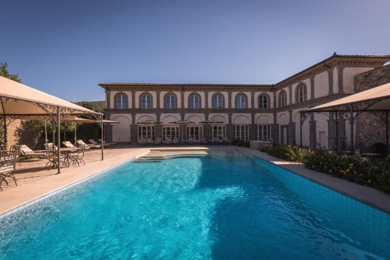 Piscina exterior con aguas cristalinas y sombrillas del Relais La Corte dei Papi en Toscana