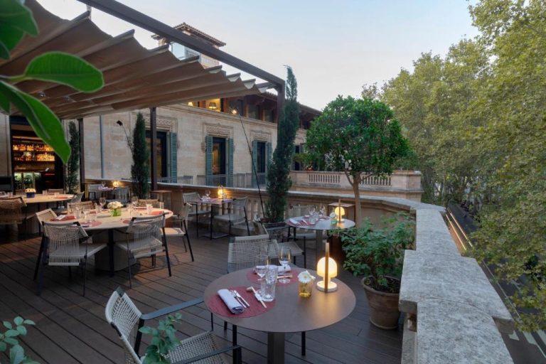 Terraza restaurante exterior del Can Alomar Hotel con mesas elegantes y vistas al edificio histórico