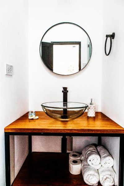 Baño moderno con lavabo de cristal y espejo redondo en WasiPai Boutique Hotel